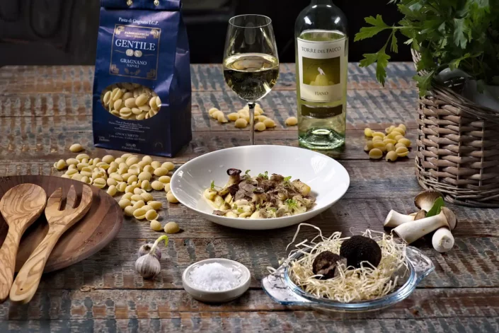 Ein liebevoll angerichteter Teller mit Gnocchetti, Trüffeln, Weißwein und Pasta-Zutaten auf einem rustikalen Holztisch für Genießer.