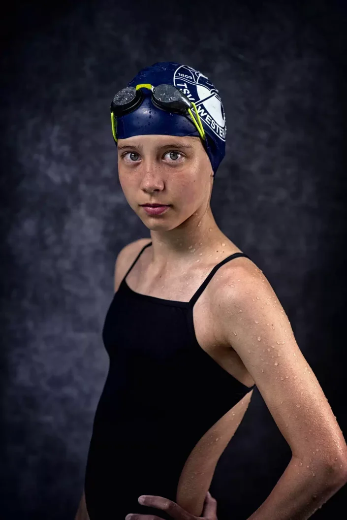 Eine junge Schwimmerin von TSV Westerland mit Badekappe und Schwimmbrille blickt ernst in die Kamera. Das Porträt entstand bei einem Fotoshooting auf der Insel Sylt.