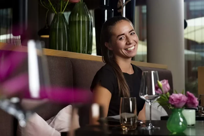 Eine junge Frau lächelt fröhlich in einem stilvollen Restaurant, ein Beispiel für professionelle Portraits und Lifestyle-Fotografie auf den Inseln.