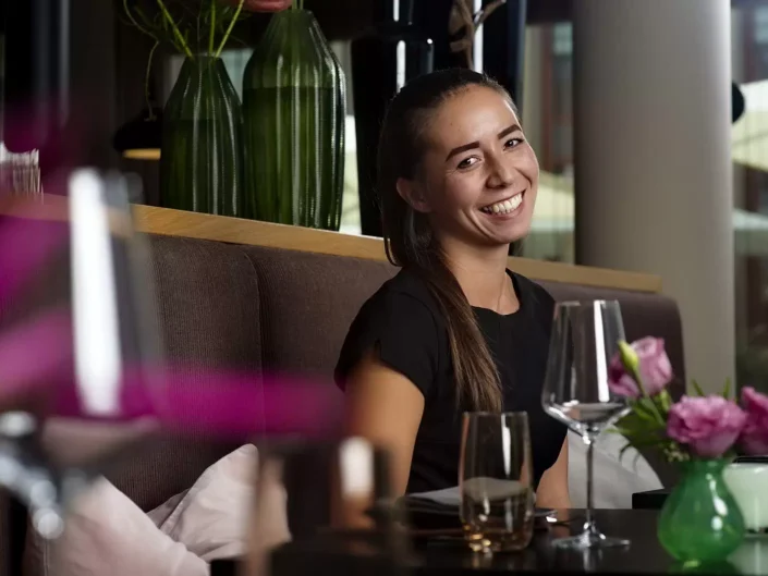 Eine junge Frau lächelt fröhlich in einem stilvollen Restaurant, ein Beispiel für professionelle Portraits und Lifestyle-Fotografie auf den Inseln.