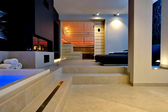 Moderner Wellnessbereich in einer Sylter Immobilie mit Whirlpool, Kamin, Sauna und gemütlicher Liegefläche in exklusivem Ambiente.