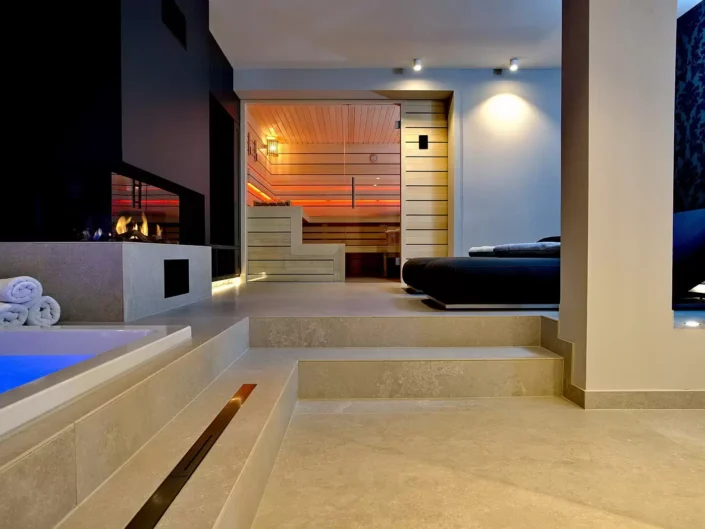 Moderner Wellnessbereich in einer Sylter Immobilie mit Whirlpool, Kamin, Sauna und gemütlicher Liegefläche in exklusivem Ambiente.