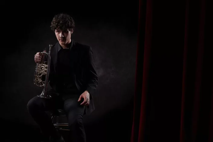 Eleganter Musiker mit Trompete vor dunklem Hintergrund, fotografiert vom Fotograf Sylt für ausdrucksstarke Portraits und künstlerische Aufnahmen.