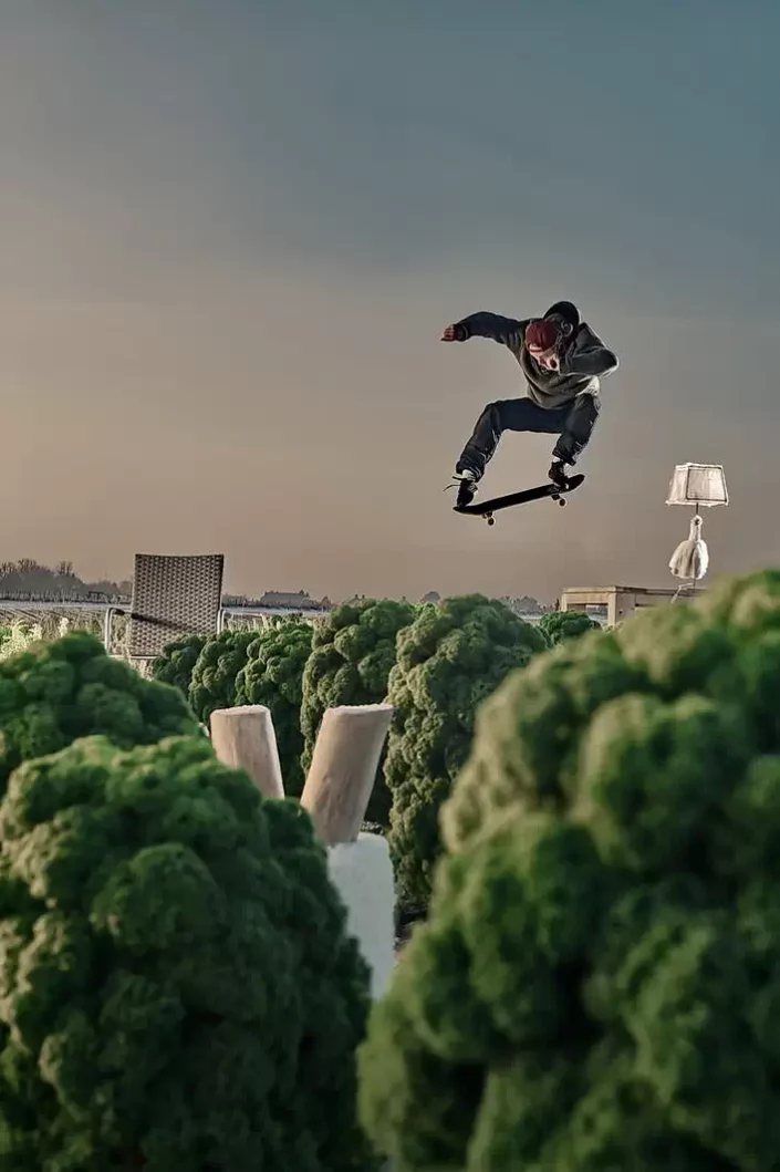 Ein Skater vollführt einen kunstvollen Sprung über Grünkohlfeldern, festgehalten in einem dynamischen Portrait für kreative Fotografie.
