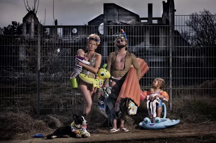Künstlerische Familienfotografie: Eltern mit Kindern und Hund in Strandkleidung vor einer Ruine, inszeniert als humorvolles Porträt.