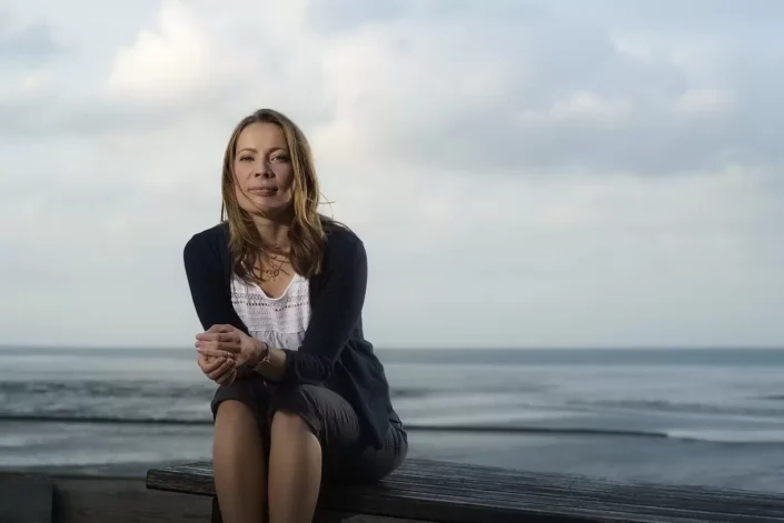 Elegantes Portrait einer Frau auf einer Bank vor dem Meer, eingefangen durch professionelle Portraits-Fotografie auf den Nordfriesischen Inseln.