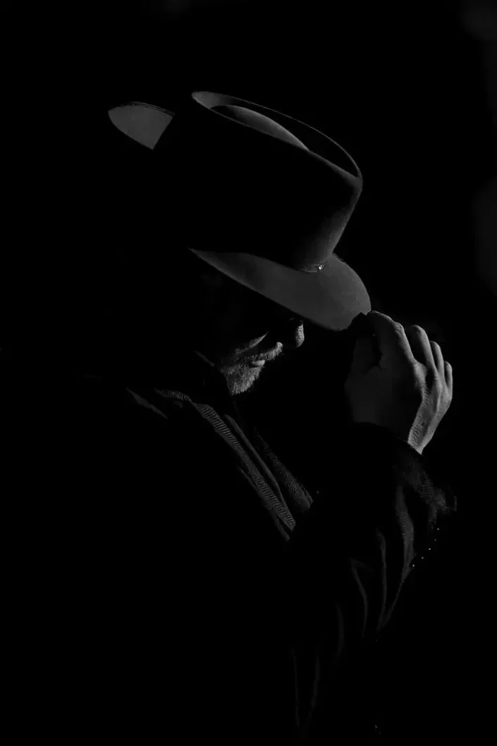 Stimmungsvolles, künstlerisches Portrait in Schwarz-Weiß: Ein Mann mit Hut im eleganten Lichtspiel für exklusive Portraits auf Sylt.