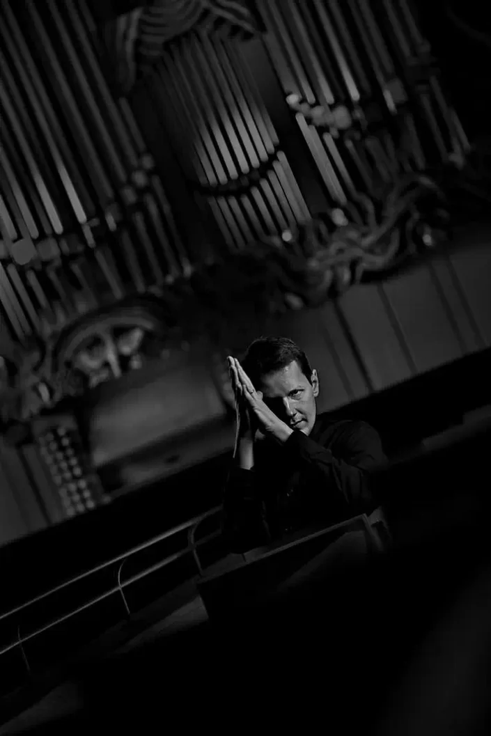 Stimmungsvolles Schwarz-Weiß-Portrait eines Mannes vor einer Kirchenorgel, das Eleganz und künstlerische Tiefe in der Portraitfotografie vereint.