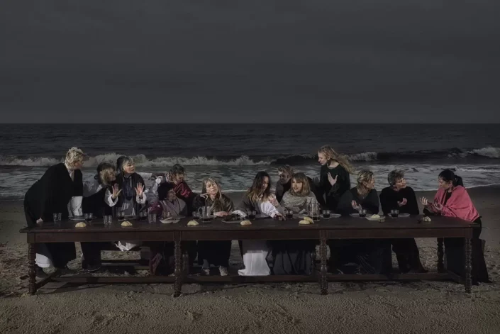 Eine künstlerische Inszenierung des Abendmahls mit einer Gruppe Frauen an einem langen Tisch am nächtlichen Strand von Sylt in Kampen für exklusive Portraits.