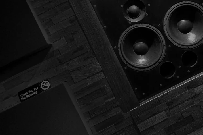 Schwarz-Weiß-Aufnahme eines Tonstudios in Hamburg mit großen Lautsprechern an einer Holzverkleidung und einem diskreten Nichtraucher-Hinweisschild an der Wand.